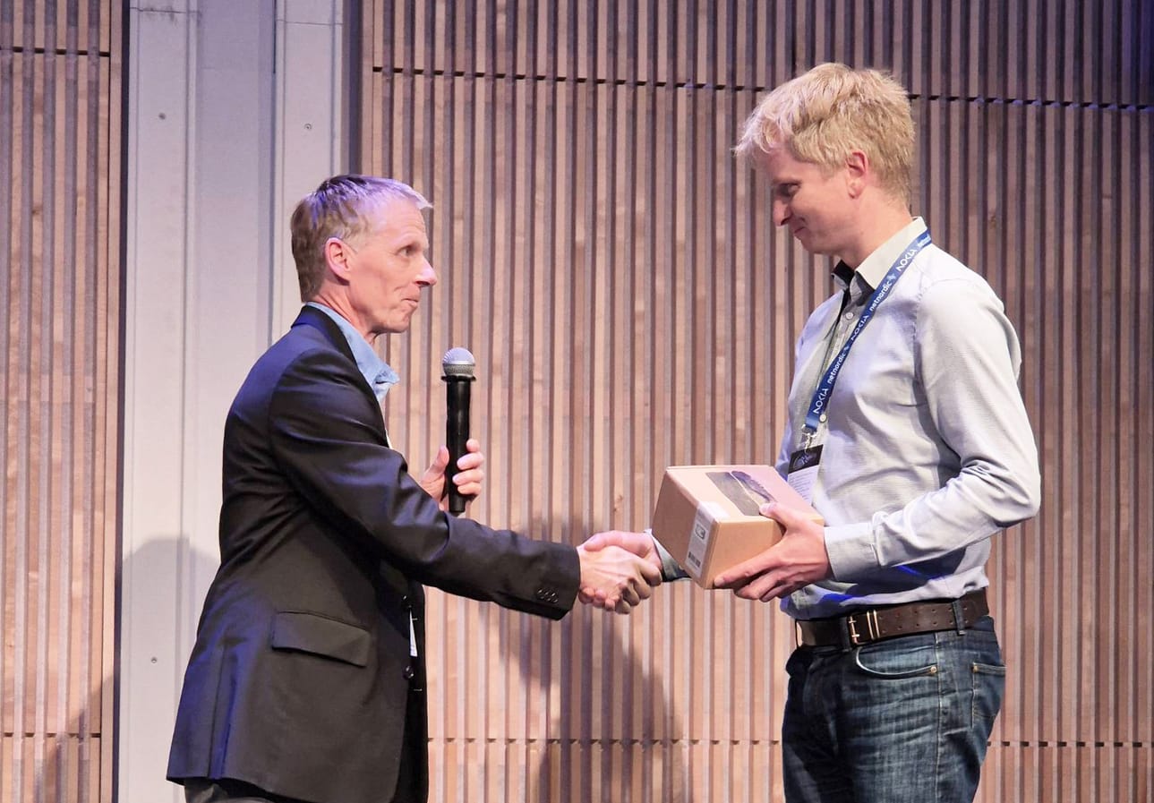 Suomen Seutuverkot ry hallituksen puheenjohtaja Jari Käyhty onnittelemassa Tampereella järjestetyssä Kuidun kiitotie -seminaaripäivässä Vuoden 2025 Valo -tunnustuksen saanutta Osuuskunta Siikaverkon Juhani Marttilaa.