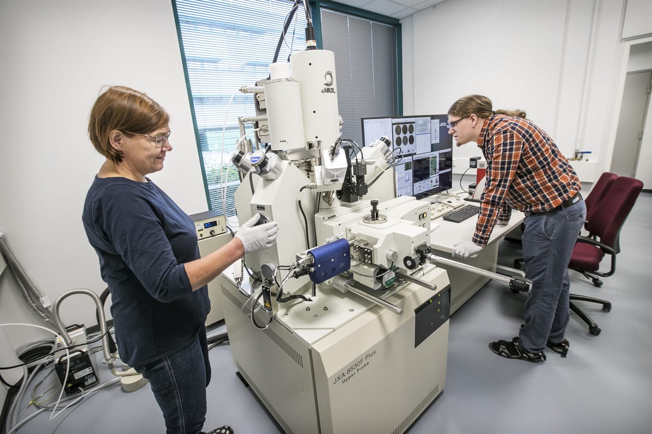 Käyttöinsinööri Leena Palmu ja geologi Marko Moilanen ja asettavat mikroanalysaattoriin näytettä.