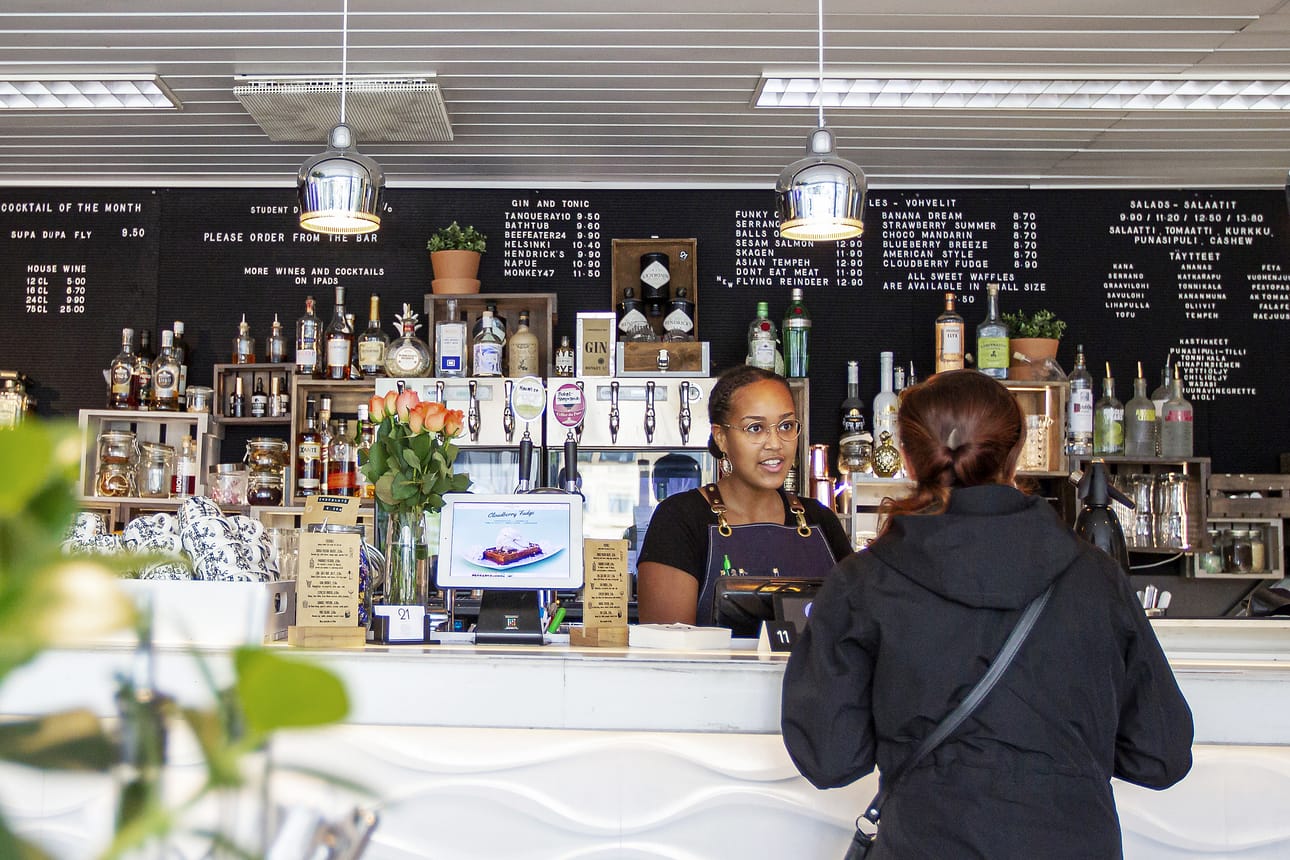Cocktail-baarina aloittaneen Cafe & Bar 21:n listalta löytyy nykyään myös vohveleita, salaatteja ja jäätelöitä. Sisustuksessa on moderni ote ja vaikutteita maailmalta. Kuvassa tiskin takana asiakasta palvelee Rosa Costa.