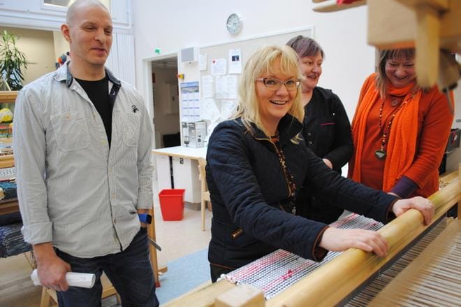 JHL:n puheenjohtaja Päivi Niemi-Laine istahti mattopuiden ääreen Tervashovissa, jota hänelle esittelivät työtoiminnan vastaava ohjaaja Tarmo Peltola ja ohjaaja Eija Lampi. Mukana seurueessa oli pääluottamusmies Eila Koskinen. KUVA:EEVA-LIISA KULJU