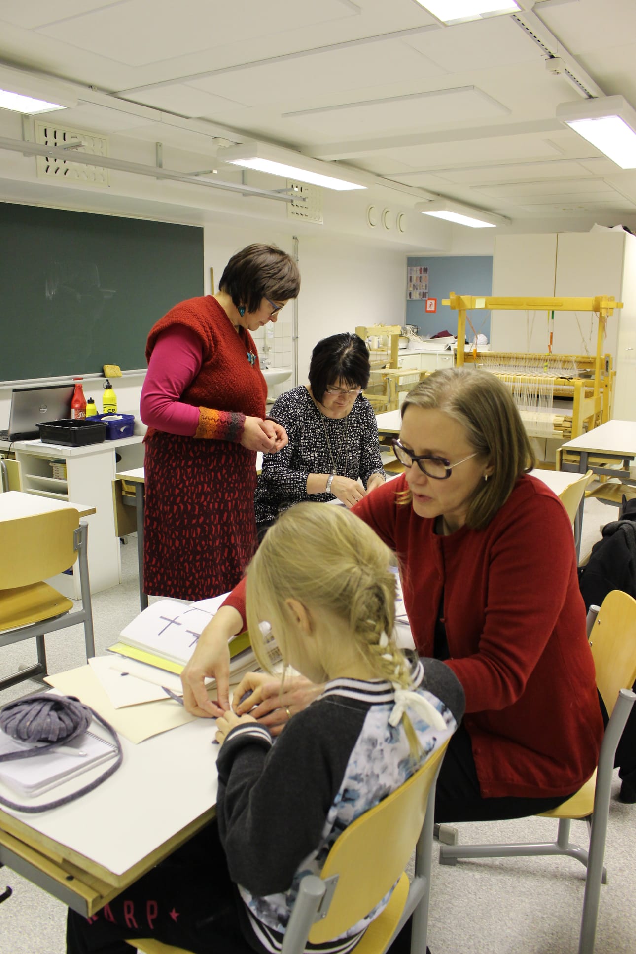 Anja Haataja ja Emmiina Pahkala innostuivat tekemään punottuja avaimenperiä. Taustalla ohjaaja Helena Turunen seuraa Sari Rimpeläinen-Knuuutisen työskentelyä.