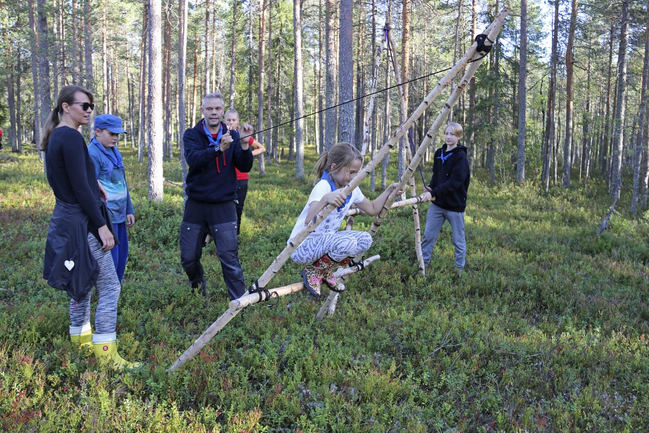Näin sitä mennään yli vesiesteen niin että heilahtaa! Stella Tapalinen pääsi kokeilemaan partiolaisille tuttua A-tukkia Ari Arolan opastuksella. Vasemmalla Stellan äiti Milla.