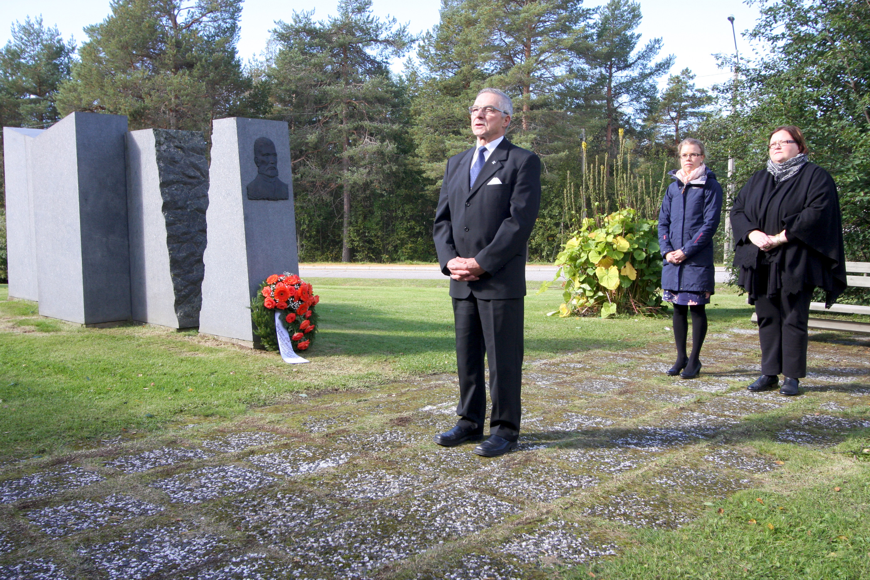 Kunnanviraston pihalla Juho Aapo Miekkasaaren monumentilla puhui sotaveteraanien Posion yhdistyksen puheenjohtaja Juhani Outila. Taustalla kukkalaitteen laskeneet kunnanjohtaja Heli Knutars (vas.) ja kirkkoherra Leena Pudas.