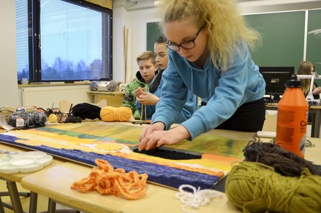 Jesse Kokko, Viivi Latva-Kurikka ja Saana Pohja virkkasivat ketjusilmukkaa yhteiseen, pehmoiseen taideteokseen. KUVAT: HANNELE YLI-VIITALA