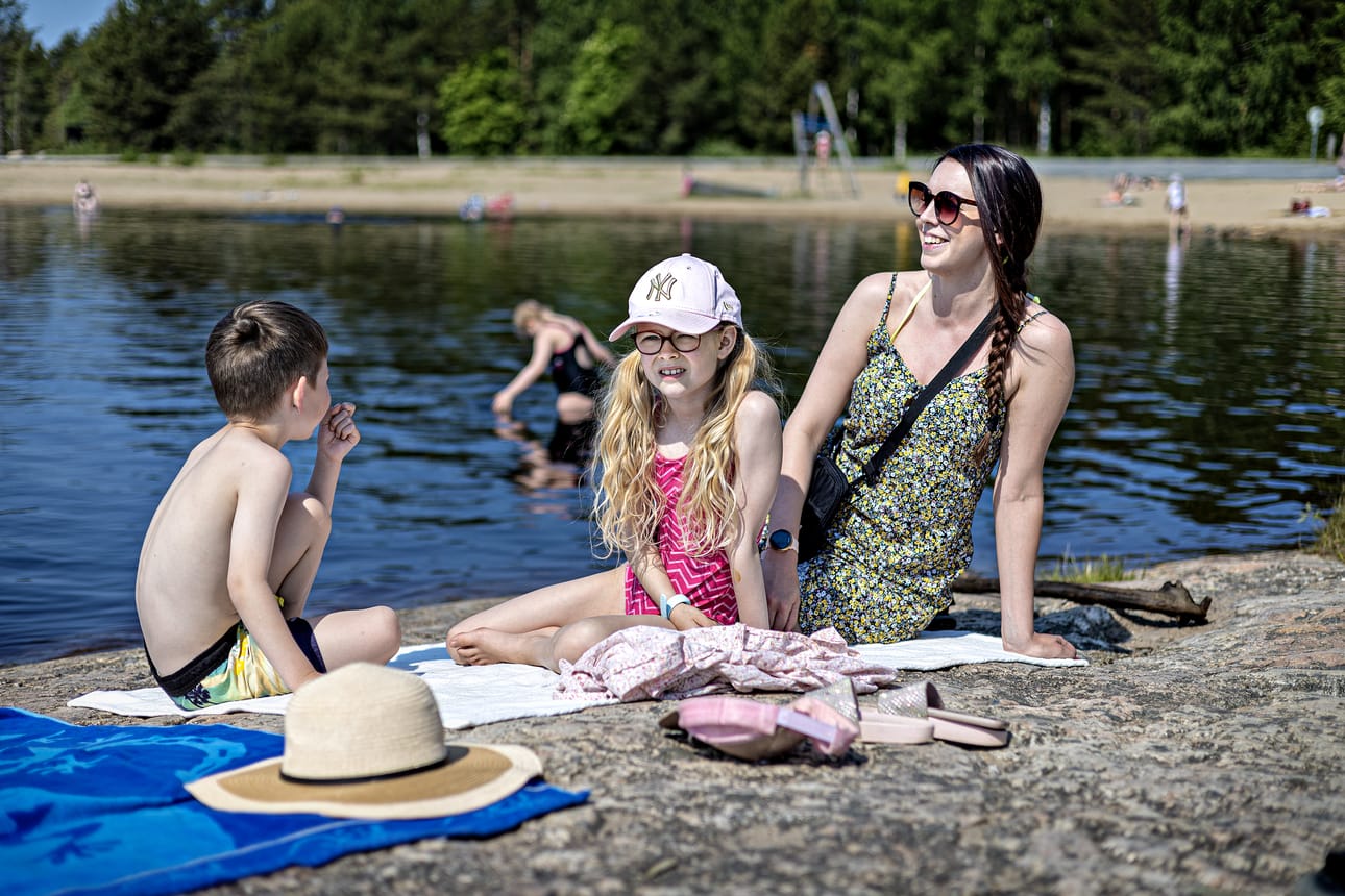 Susanna Saikkonen sekä Leevi, Elviira ja Viliina (vedessä) nauttivat kesästä Kyrkösjärven rannalla torstaina.