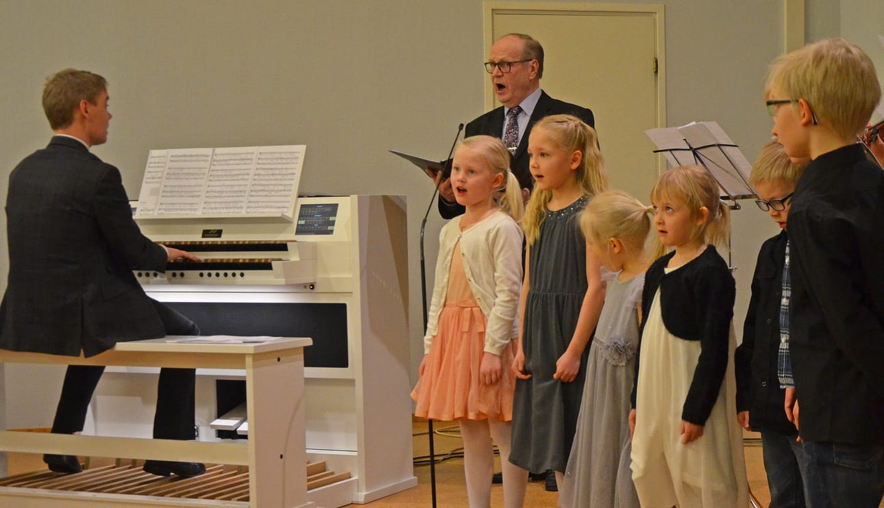 Vesa Kajava (vas.), Teuvo Kajava ja lapsenlapset Oona, Julia, Venla, Veera, Aleksi, Tuukka ja Niko musiikki-illassa Posion seurakuntatalolla.