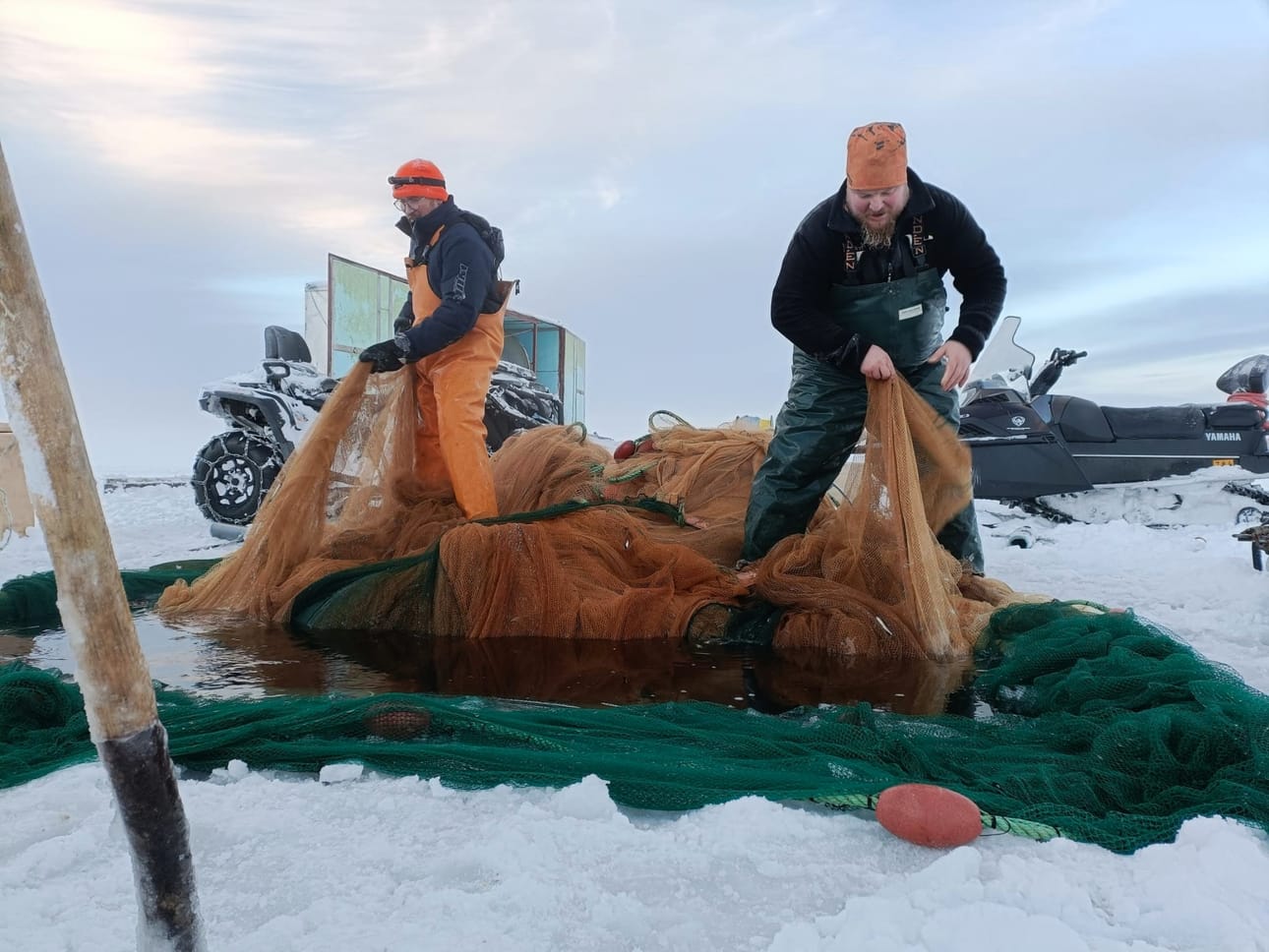 Koillismaalla ja Kainuussa rekrytoidaan uusia kaupallisia kalastajia mestari-kisälli-mallilla, jossa kokeneet kalastajat siirtävät tietotaitoa nuoremmille. Kuvassa Pekka Kajava (vas.) ja Jari Pitkänen ovat talvinuotalla Kuusamon Muojärvellä joulukuussa 2025. Jo 35 vuotena talvinuotalla käyneellä Kajavalla on ollut yksi kalastajakisälli, ja toinen on kohta aloittamassa.