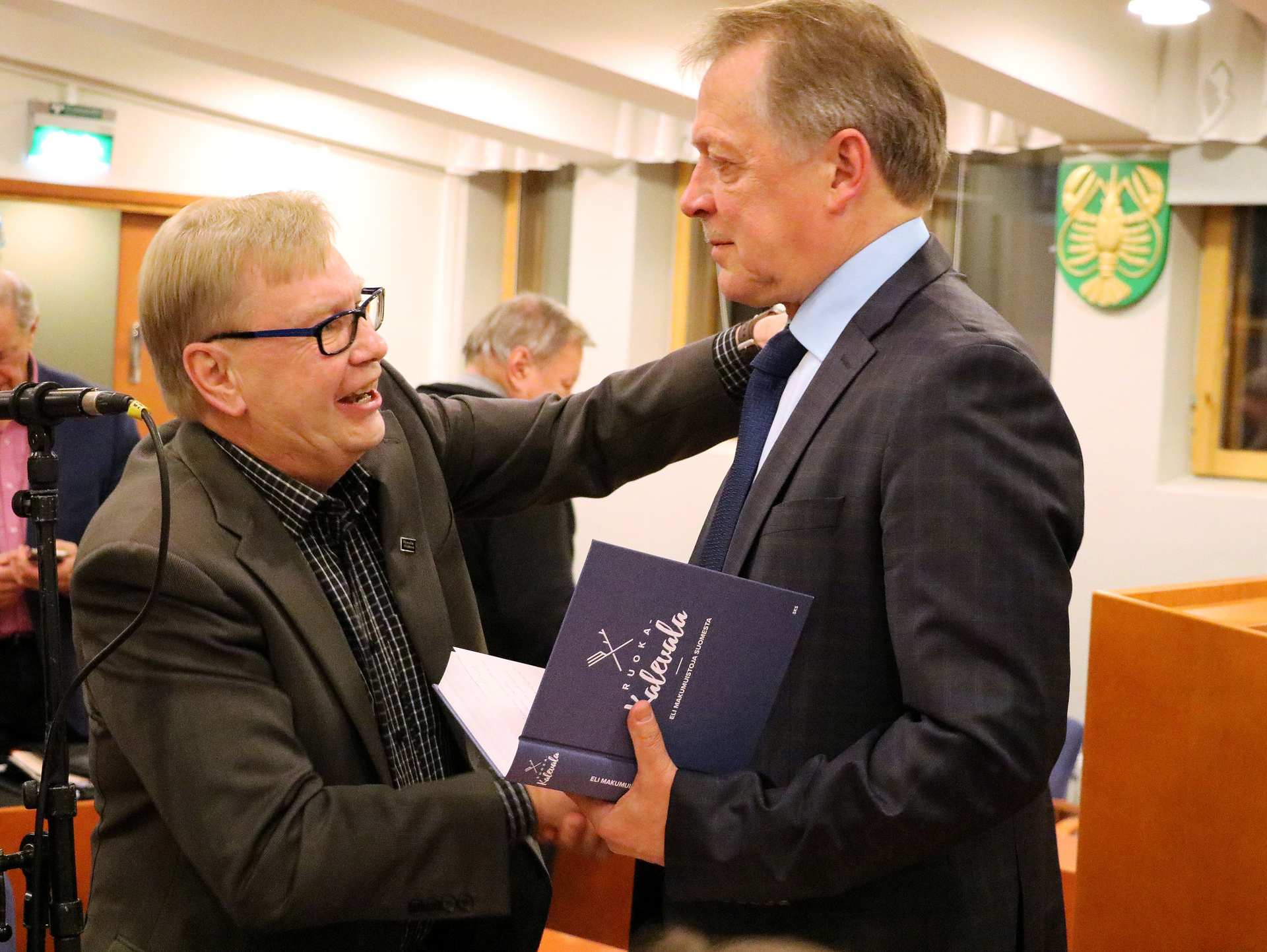 Hannu Kaartinen sai valtuutetuilta ja virkamiehiltä lämpimät onnittelut valintansa jälkeen. Ensimmäisten joukossa onnittelemassa RuokaKalevala-teoksen lahjoittanut Keijo Pylväs (vas.)