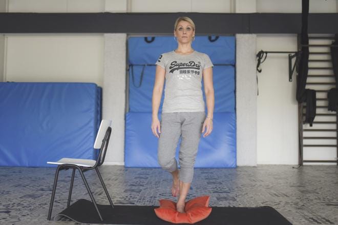 Fysioterapeutti ja pilateskouluttaja Hanna Kanerva neuvoo seisomaan yhdellä jalalla tyynyn päällä. Näin nilkka joutuu työskentelemään ja tasapaino kehittyy. KUVA:
