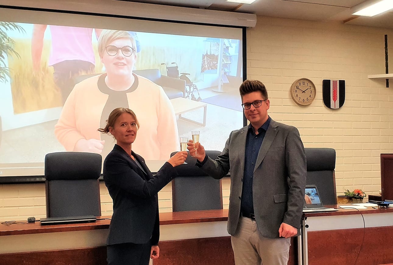 Kunnanhallituksen puheenjohtaja Pia Jaakkola (kesk.) ja kunnanjohtaja Juha Herrala iloitsevat velattomuudesta. Taustalla on videotallenne valtiovarainministeri Annika Saarikon (kesk.) pitämästä maljapuheesta kunnanhallitukselle.