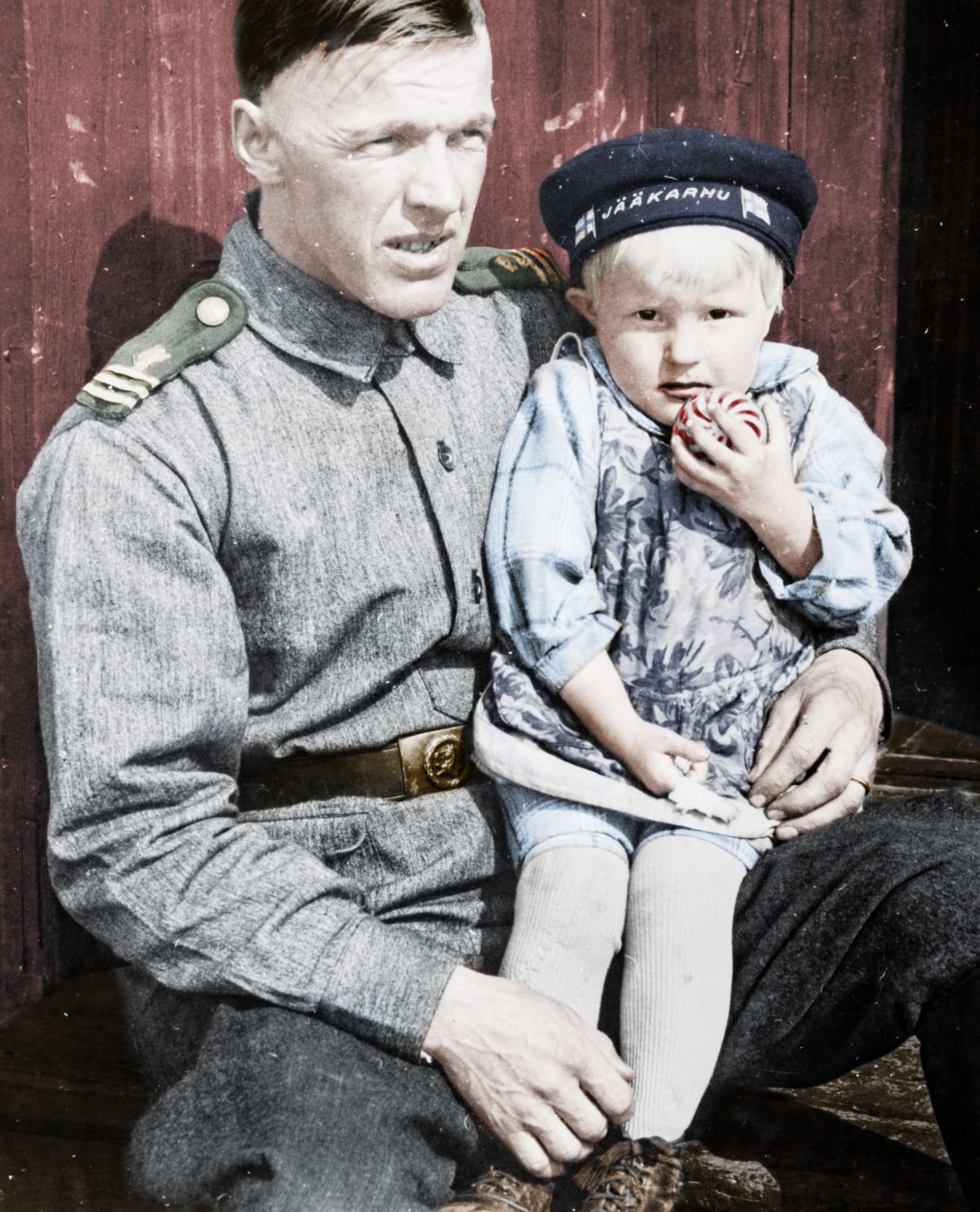 Kuusamon rajakomppanian kersantti Paavo Ojala polvellaan Anneli-tyttö, jolla on päässä Suomen lipuilla varustettu Jääkarhu-baskeri. Ojala syntyi Teuvalla 4.7.1905 ja kaatui talvisodan taistelussa Sallassa 11.1.1940. Ojalan puoliso oli kuusamolainen Anna Johanna Waarala, jonka isä Juho Waarala oli maanviljelijä, kunnankirjuri ja itsenäisen Suomen ensimmäinen kuusamolainen kansanedustaja.