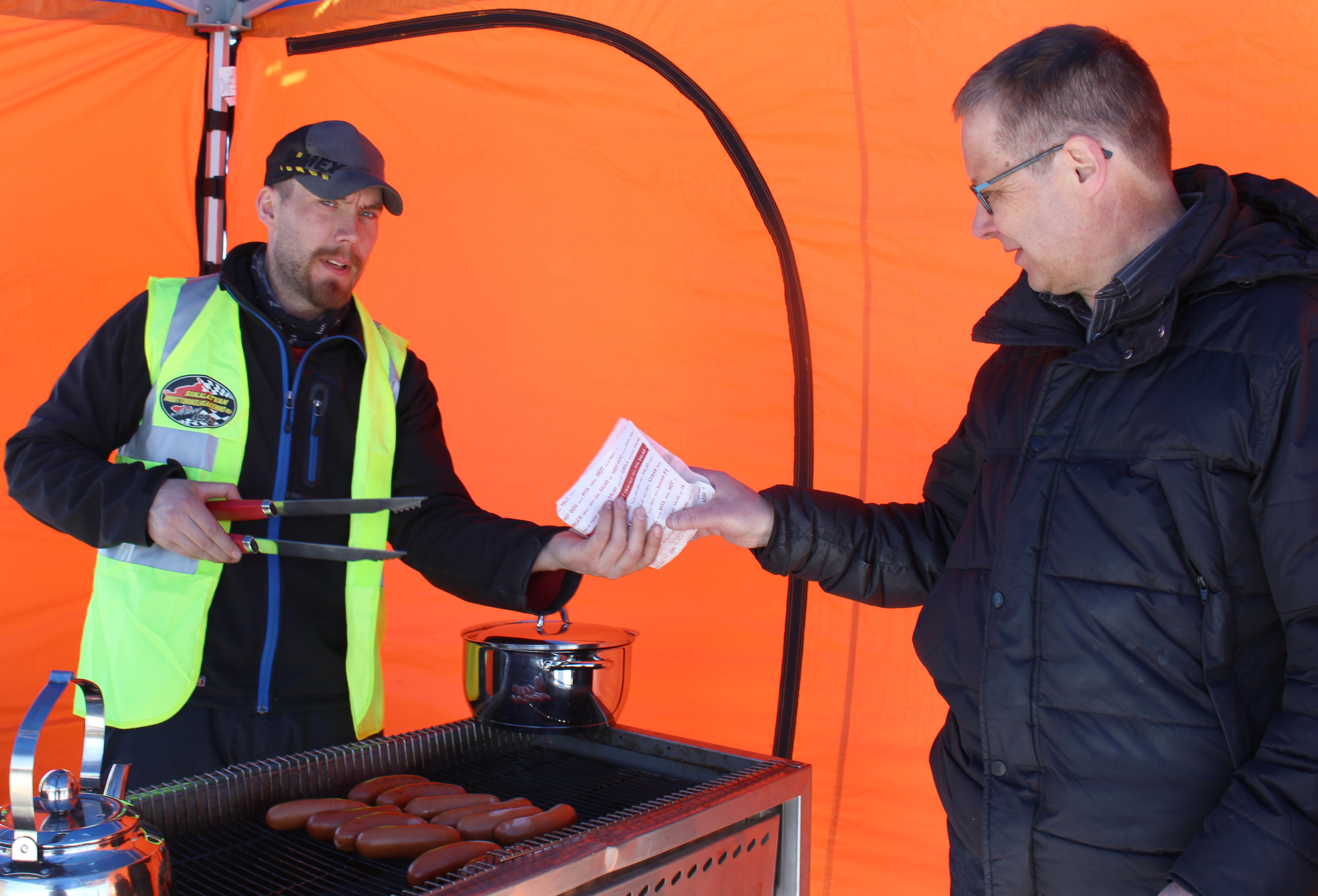 Siikalatvan Moottorikelkkakerhon uusi puheenjohtaja Jarkko Väyrynen oli vastuutettu makkaran myyntiin Orsiniemen Snowcross-radan avajaistapahtumassa. Makkarakojulla ostoksilla Timo Aitto-oja.