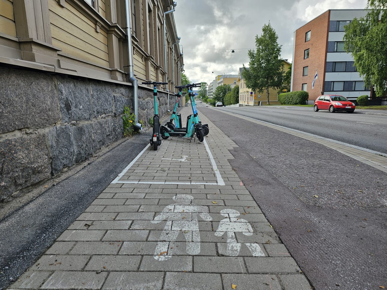 Koulukadulla sähköpotkulautojen pysäköintipaikka kaventaa jalkakäytävää huomattavasti.
