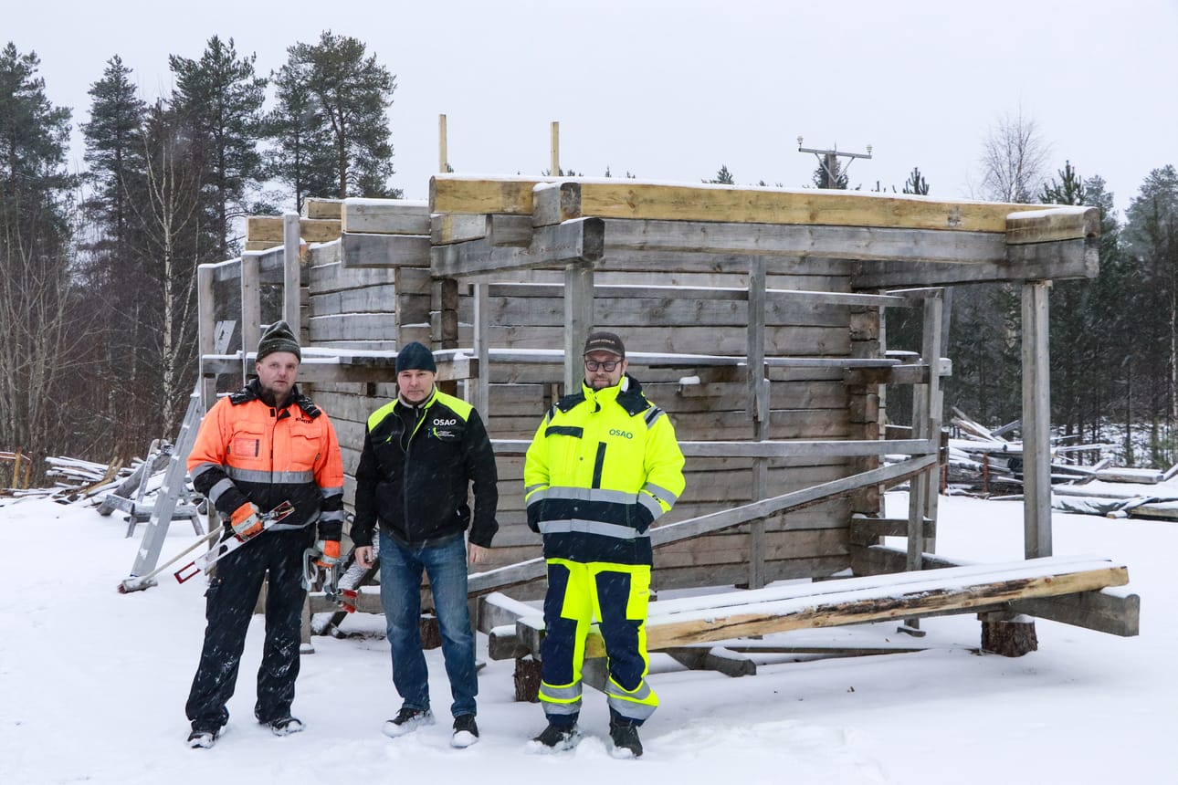 Kurssilla opiskeleva Jouni Vengasaho, lehtori Jari Ruutikainen ja opettajana toimiva Marko Kehusmaa keskeneräisen hirsikehikon edessä.