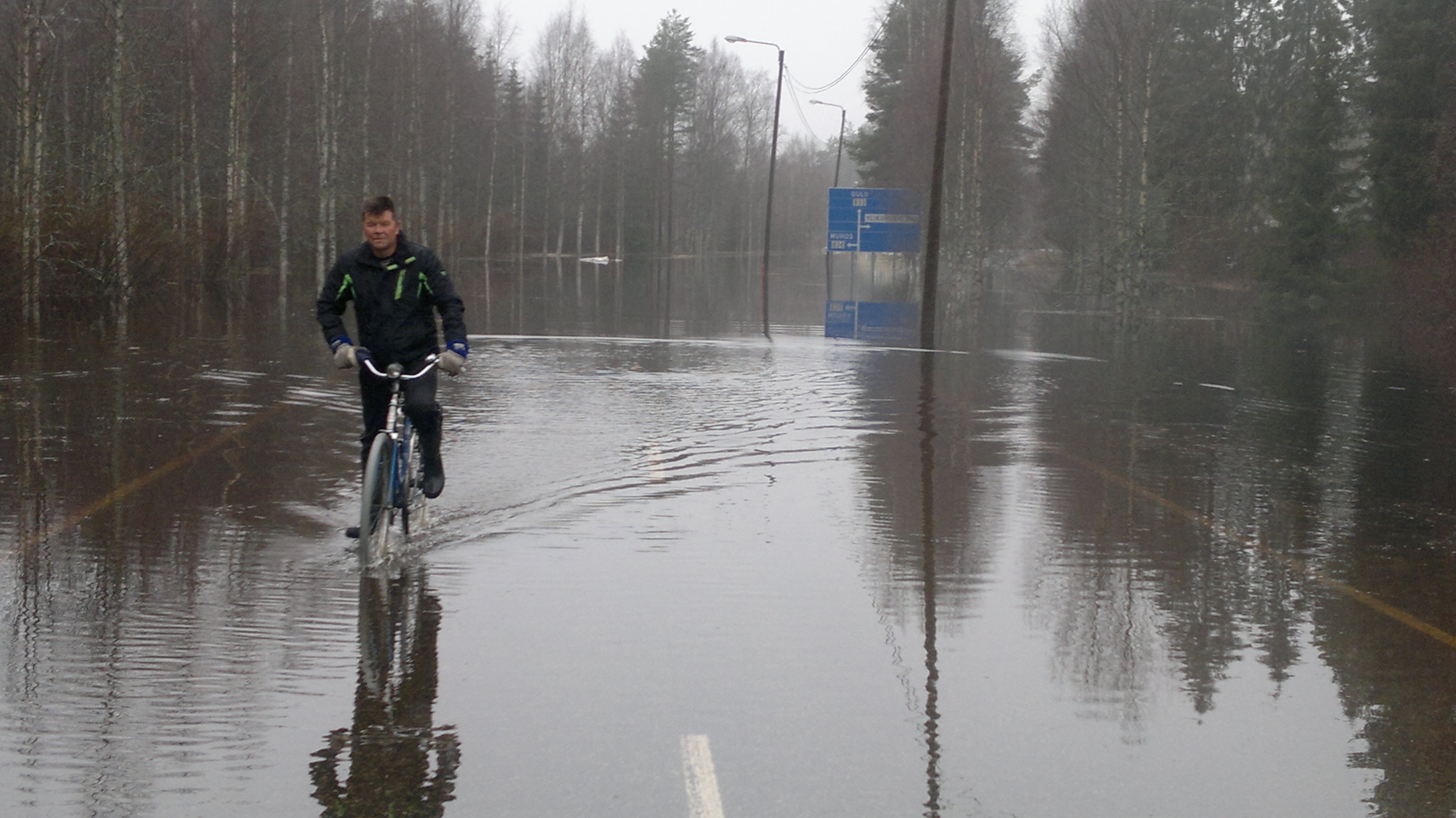 Ouluntie on poikki tulvan vuoksi Ylikiimingin kirkon kohdalla. Heikki Ukonmaanaho polkee pyörällä Oulun suunnasta. 