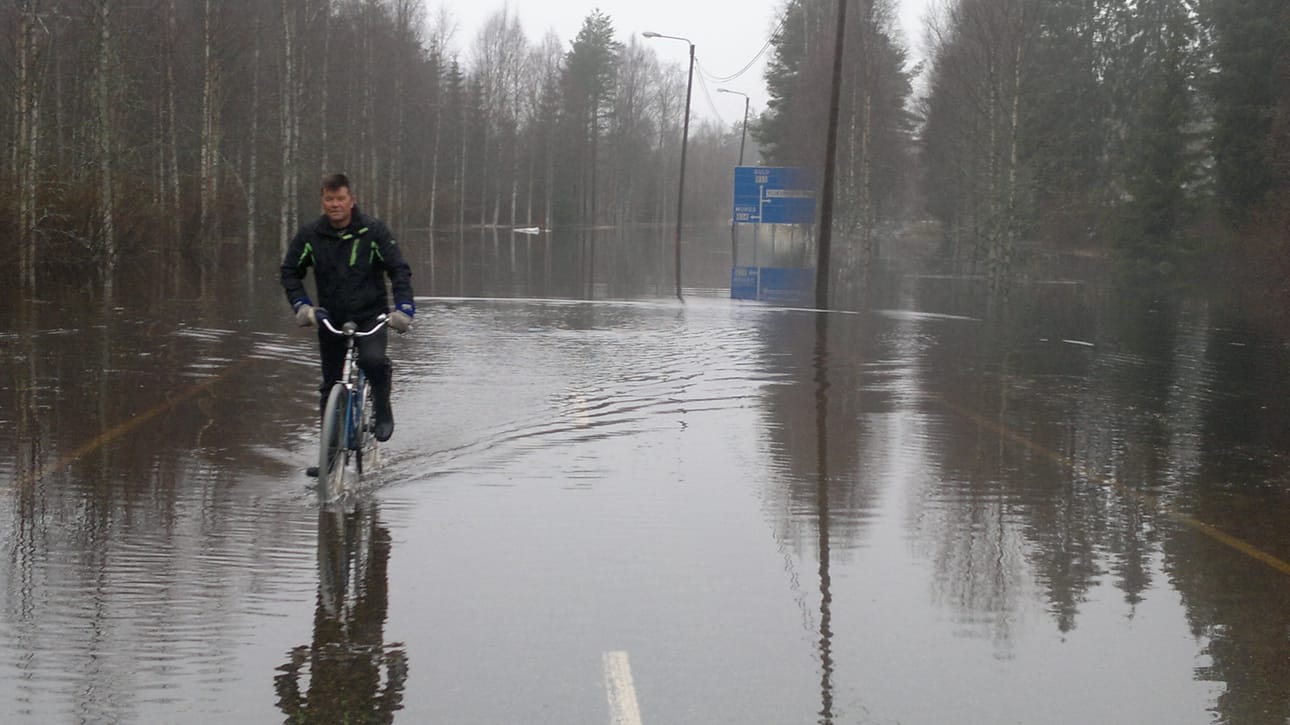 Ouluntie on poikki tulvan vuoksi Ylikiimingin kirkon kohdalla. Heikki Ukonmaanaho polkee pyörällä Oulun suunnasta.