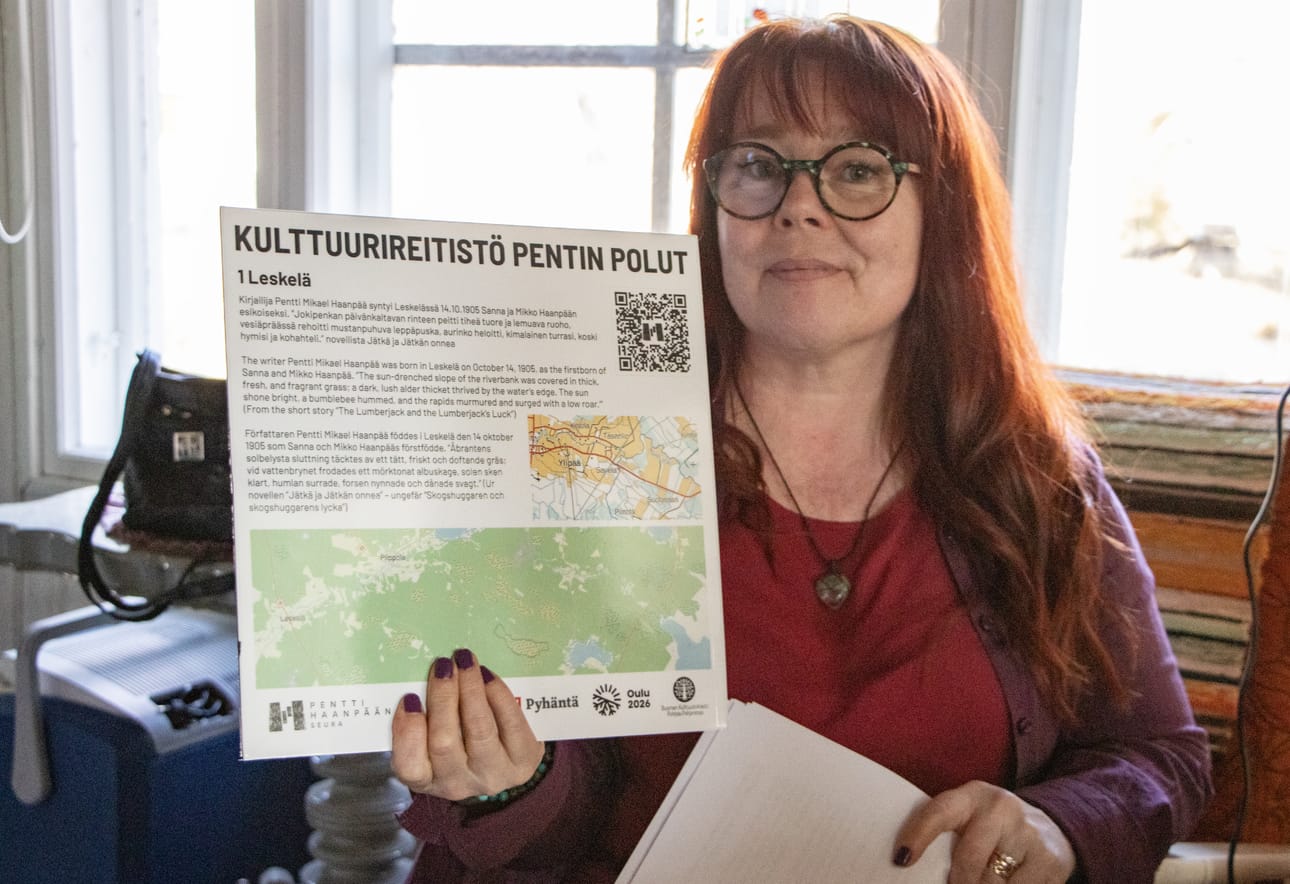 Riikka Kononen näyttää esimerkkitaulua, joita tulee kulttuurireitistön varrelle. Infotaulun QR-koodin kautta pääsee kuuntelemaan katkelmia Pentti Haanpään tuotannosta.