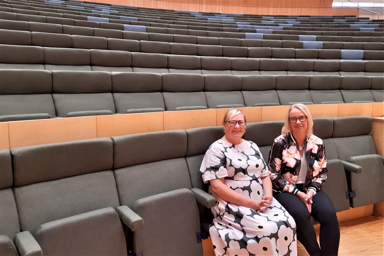 Mustasaaren kulttuuritalon auditorion yleisilme muuttui entistä rauhallisemmaksi, kun tuolit päällystettiin vihreällä ja sinisellä villakankaalla. Suunnittelija Leena Havu-Erhie ja vs. rehtori Monika Fröjdö ovat tyytyväisiä uudistuneisiin tiloihin.