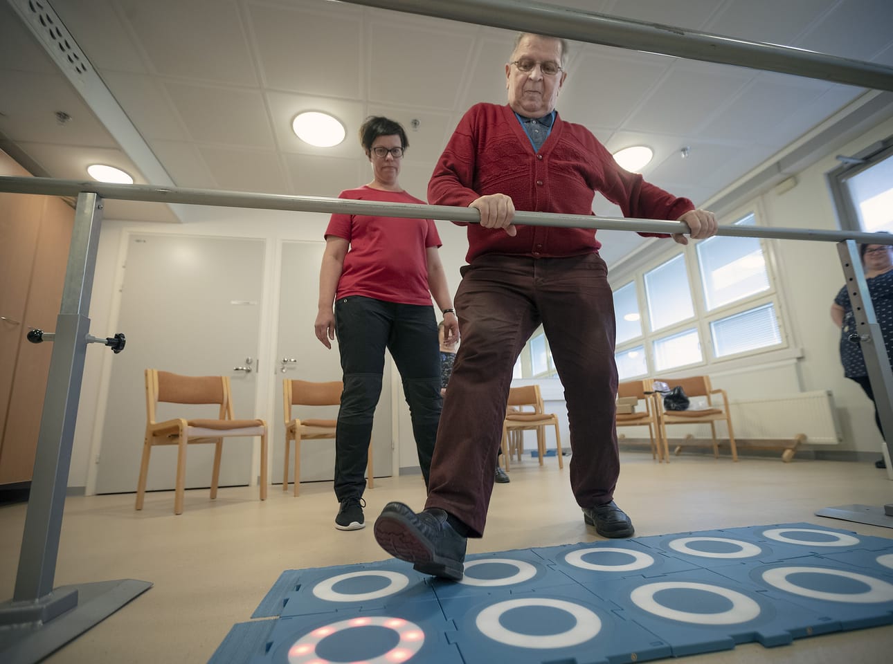 – Ihan mahtavaa, kun oppii, miten tämä toimii, kehuu Moto Tiles -liikuntalaattoja testannut Helmerin päivätoiminnan asiakas Tauno Kiviniemi. Fysioterapeutti Virpi Pumpanen ja päivätoiminnan ohjaaja Jenni Ekonoja seuraavat pelin sujumista.