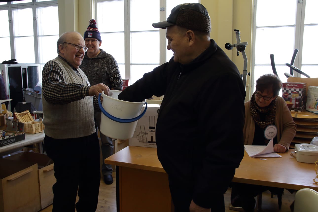 Myyntinäyttelyn päätteeksi arvottiin palkinnot. Tapahtuman puuhamiestä Jaakko Jukkolaa naurattaa. Pöydän takana istuu arpahommasta huolehtinut Ritva Pihlajamaa.
