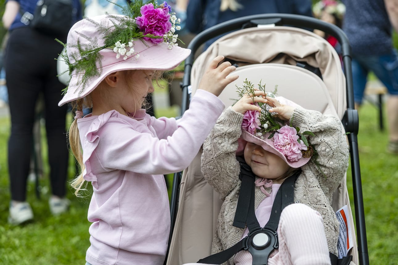 4-vuotias Livia Soppela sovittaa kukkakranssia pikkusiskonsa Seelan päähän.