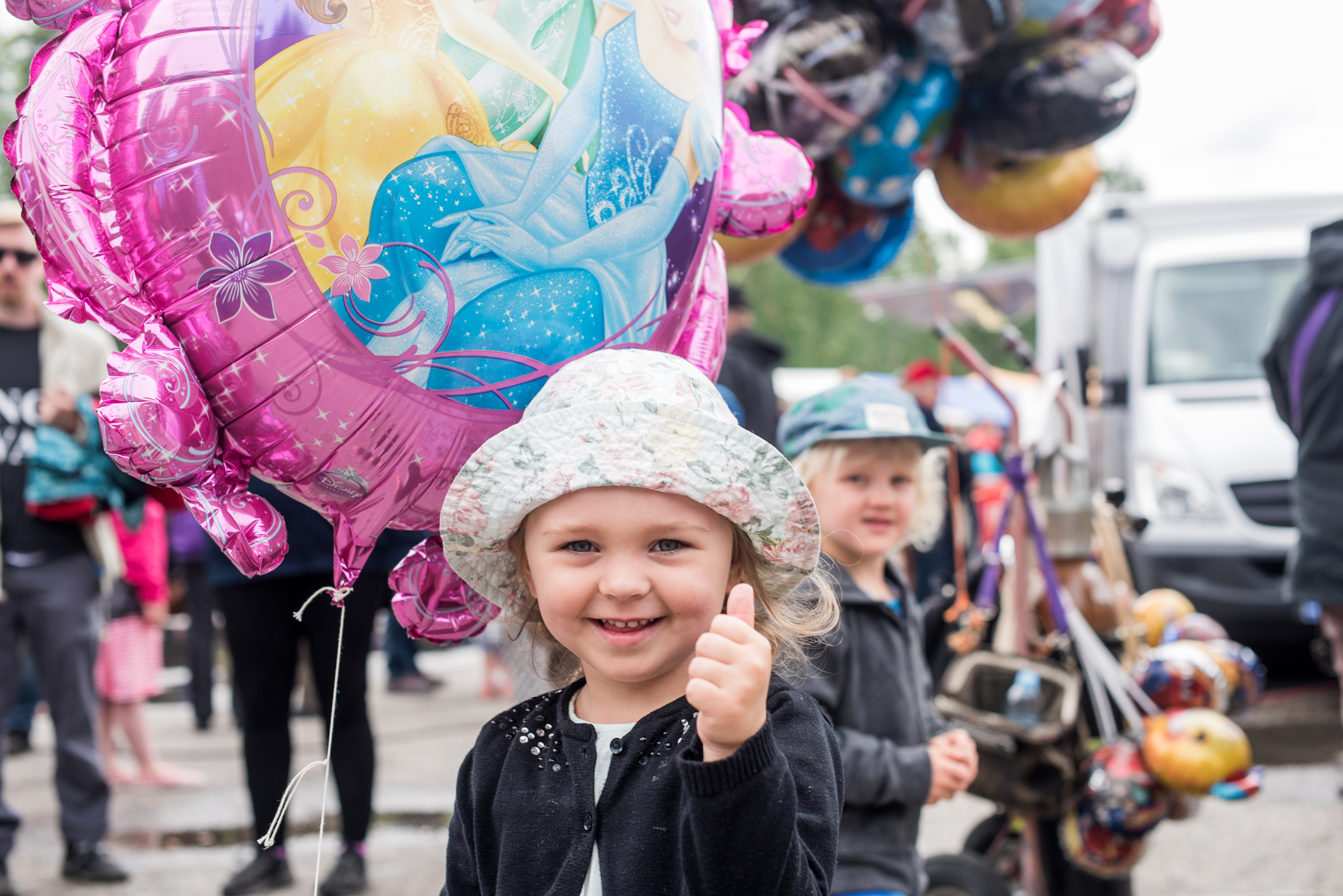 3-vuotias Ella Hietala näyttää iloisena peukkua Muikkumarkkinoille, tai ainakin jättisuurelle prinsessapallolleen.