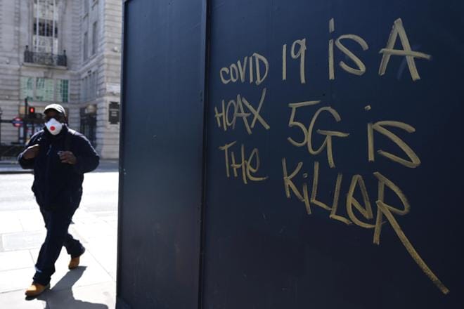 Kasvonsa suojannut mies ohitti viime viikolla Lontoossa graffitin, jossa koronaviruksen aiheuttamaa tautia kuvattiin huijaukseksi. KUVA: NEIL HALL/EPA