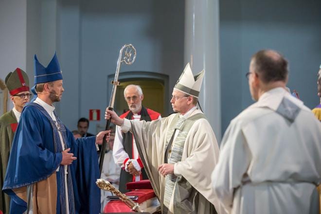 Arkkipiispa Kari Mäkinen (oik.) ojensi sunnuntaina Helsingin piispaksi vihitylle Teemu Laajasalolle (vas.) piispansauvan vihkimessussa. KUVA: Markku Pihlaja / Kirkon kuvapankki
