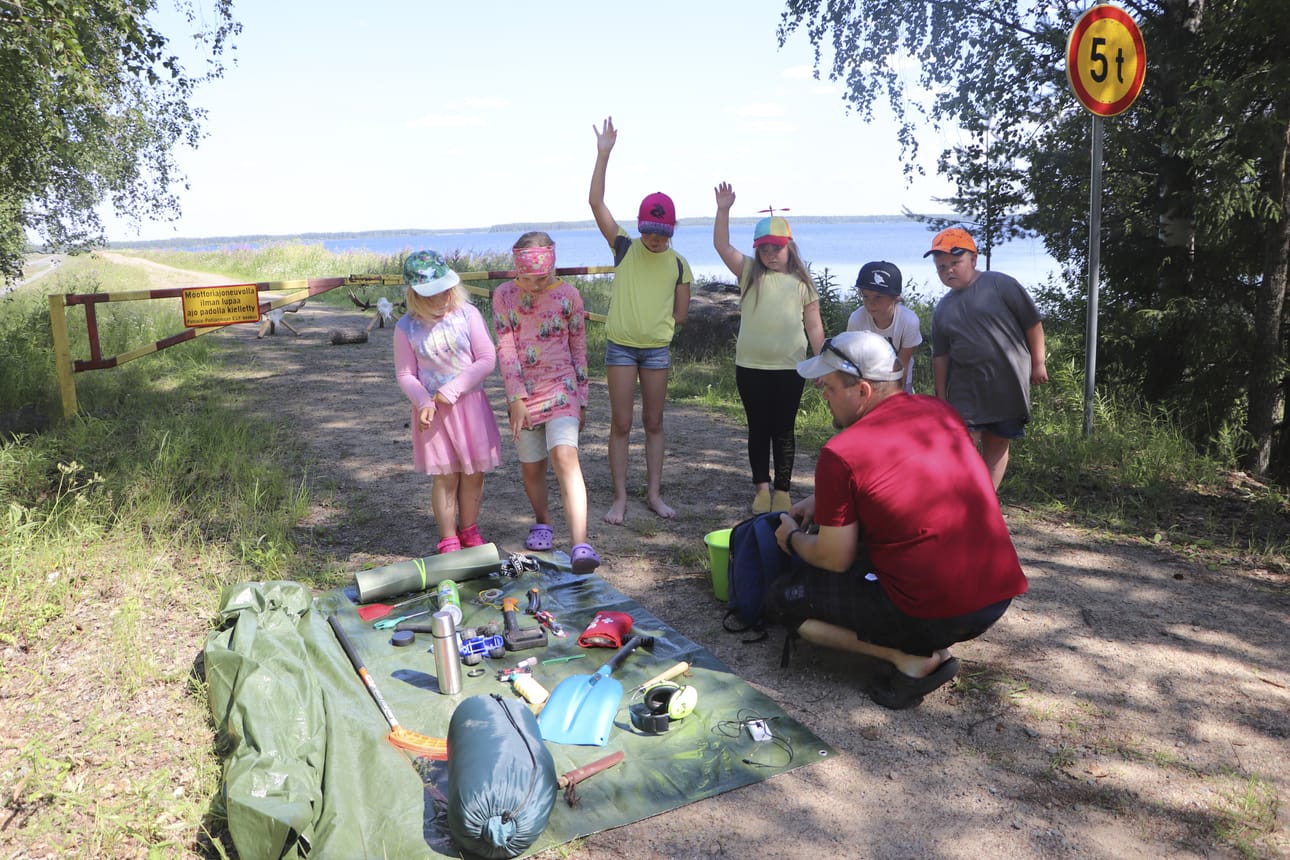 Mitä marjaretkelle kannattaa ottaa mukaan? Millä tarvikkeilla metsässä pärjää? Pulkkilan Erän Pekka Ojanaho käy varusteita läpi luontopäivään osallistuneiden lasten kanssa.