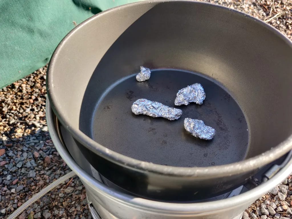 Kaasutrangialla voi säätää lämpöä, ja kun kattiloita on kaksi, niistä voi tehdä uunin laittamalla kattilat sisäkkäin ja väliin vaikka kiviä.