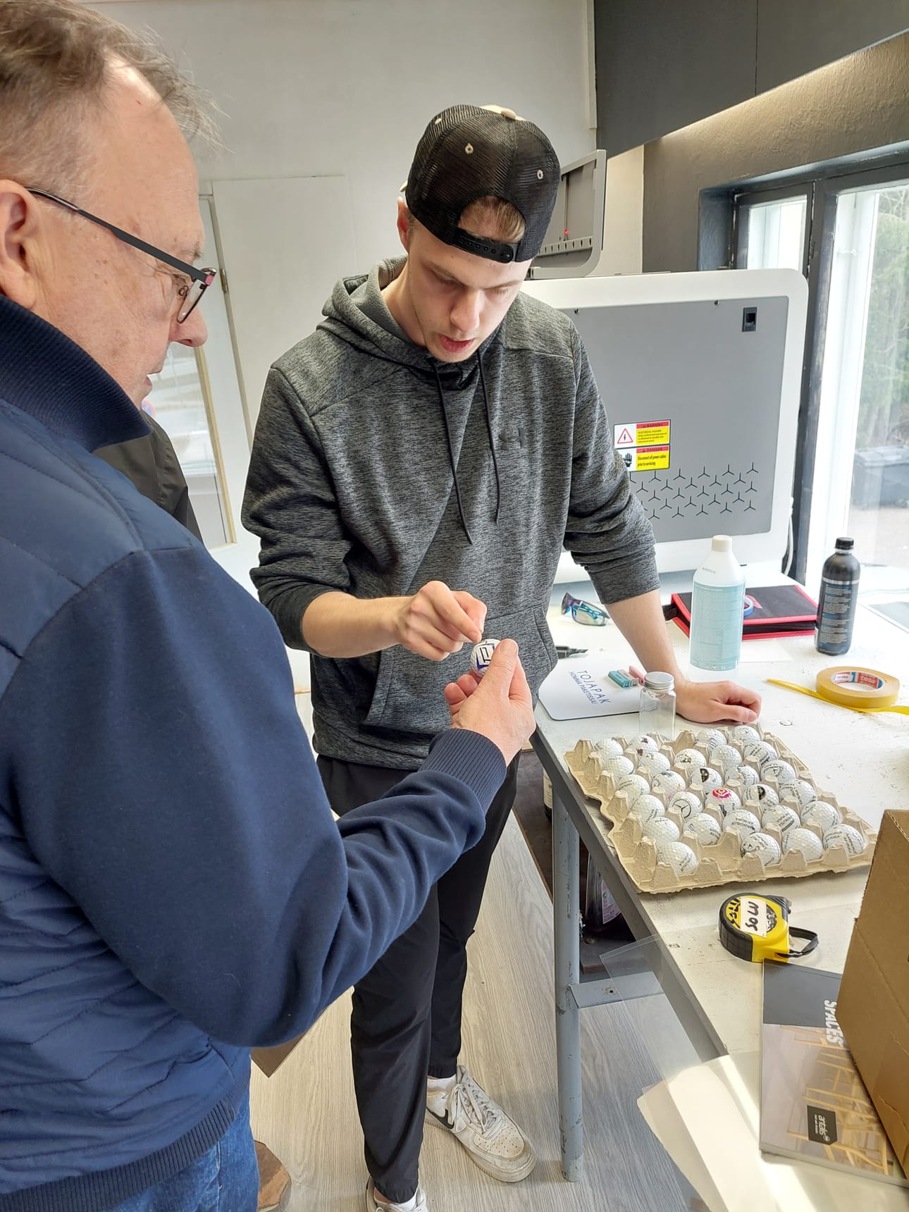 Miku Laurila on harjoitellut uudella UV-tulostimella jo reilun parin kuukauden ajan. Laurila esitteli Sauli Lehtikankaalle golfpallojen tulostusjälkeä.