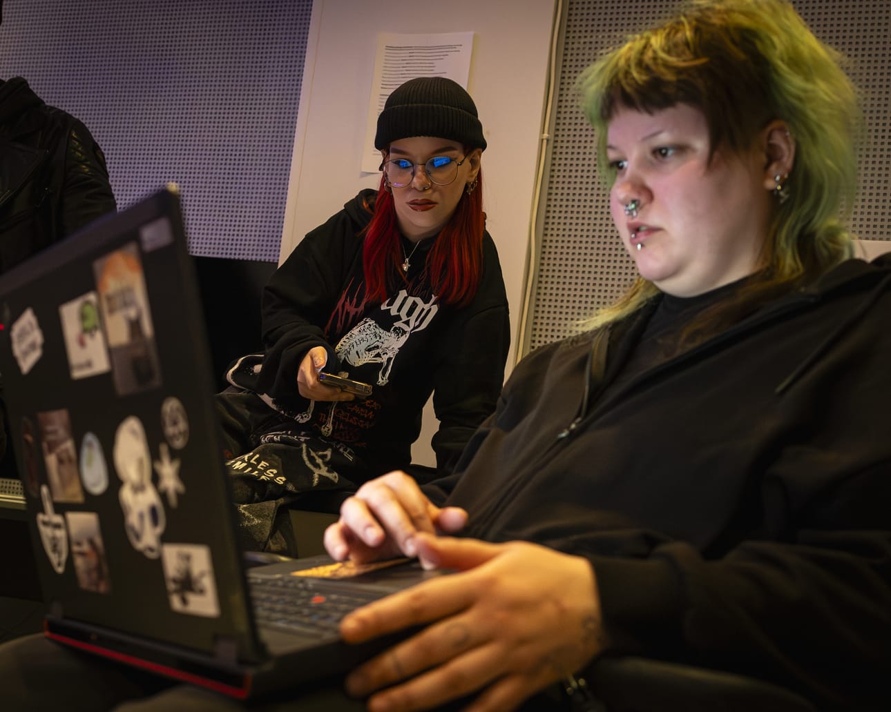 Miku Niemelä (edessä) tutkii kannettavaltaan julisteita, joita hän on tehnyt Untorockin artisteista. Moona Väärälä seuraa vieressä.