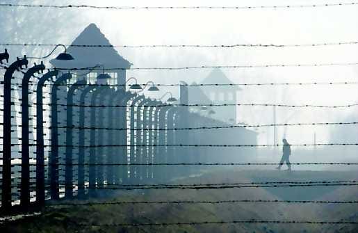 Piikkilankaa. Turisti lähestyy Auschwitz-Birkenaus aitaa ja vartiotorneja. Torstaina tulee kuluneeksi
