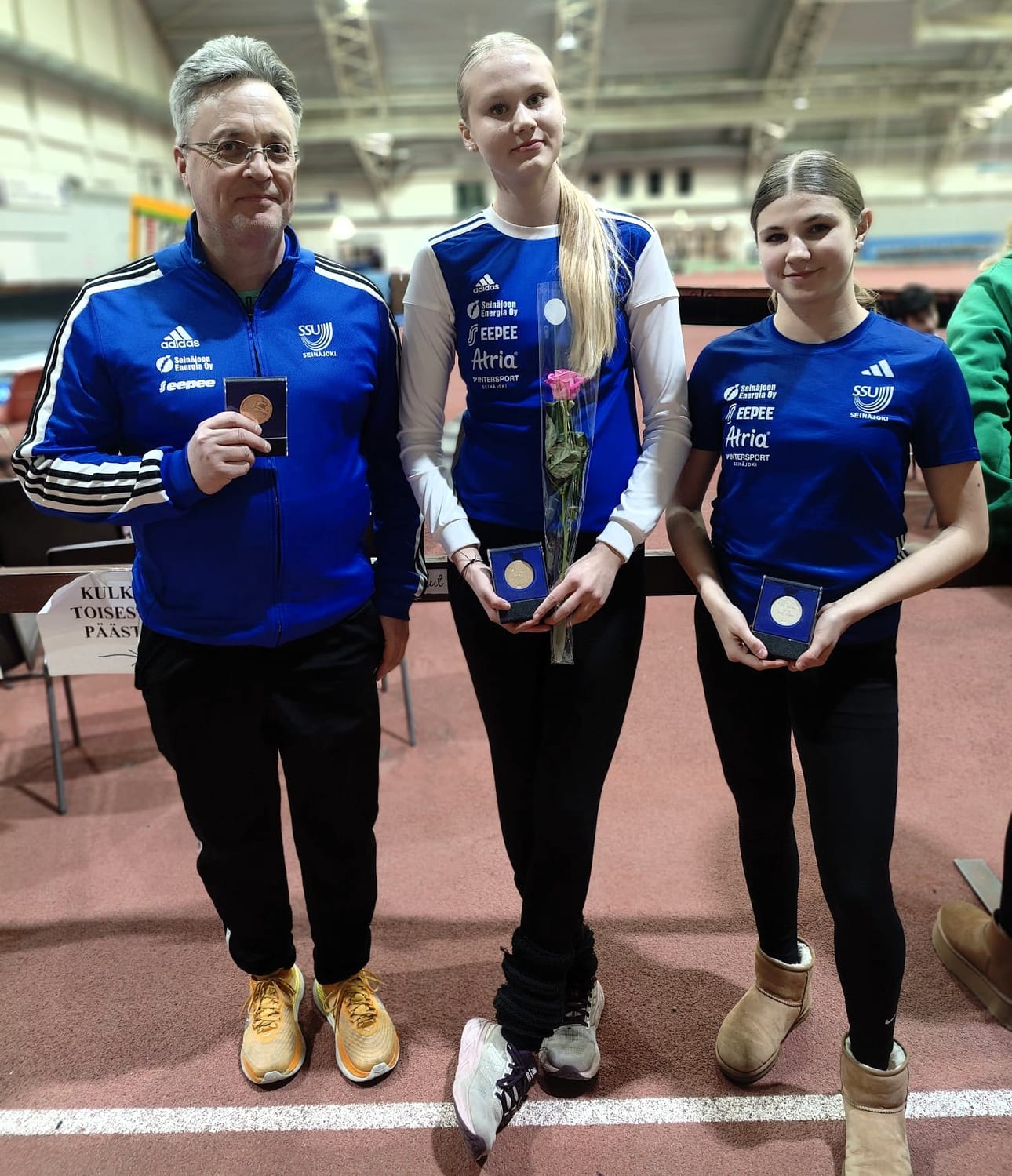 SSU:n valmentajiin kuuluva Ari Vekola ja urheilijat Emmi Ahvenlampi ja Iines Tuhkanen mitaleiden kera Jyväskylän SM-hallikisojen jälkeen.