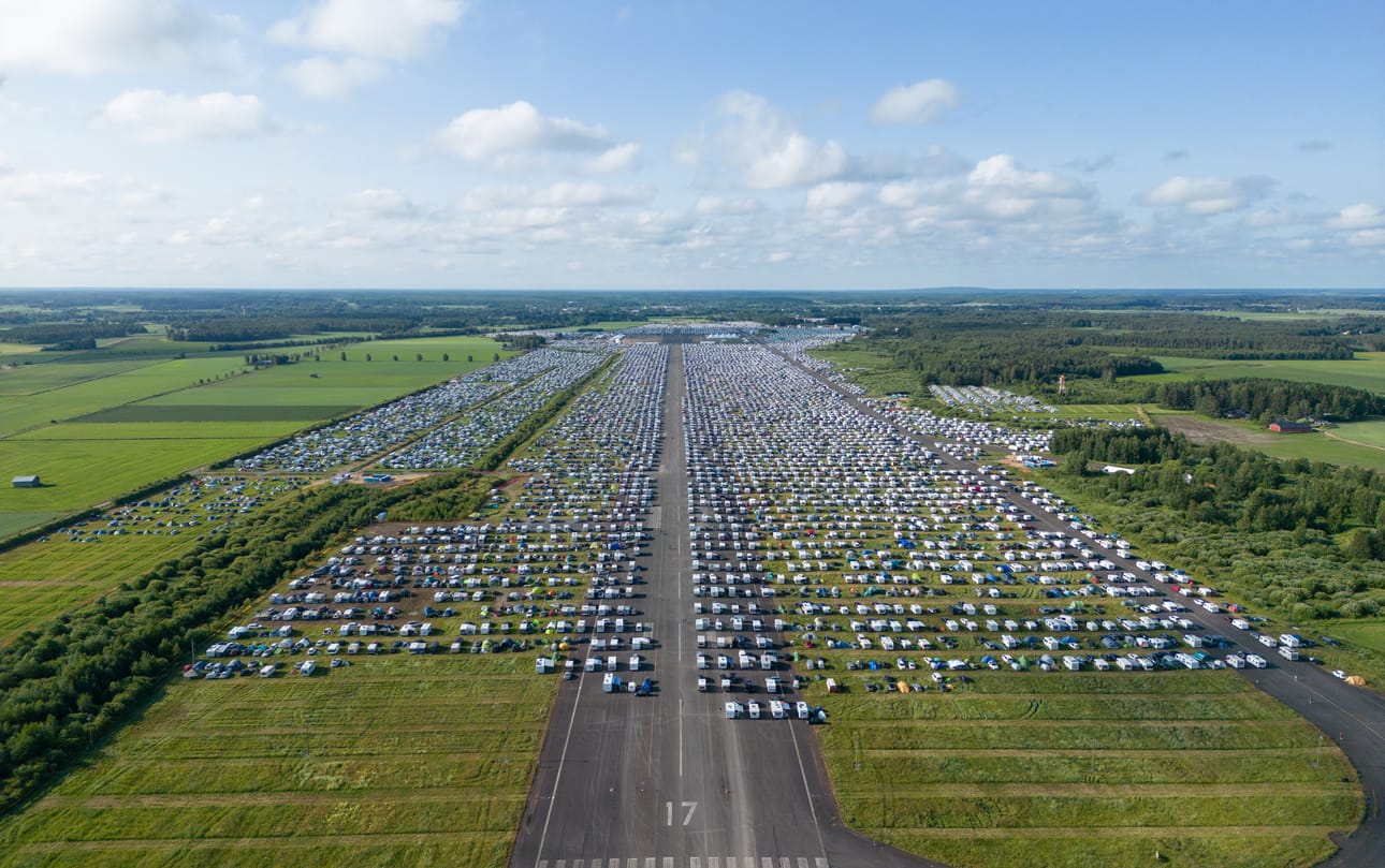 Seuravieraita varten lentokenttäalue oli jaettu noin 13 000 majoitustonttiin. Tuhansia ihmisiä vetävä seurateltta häämöttää asuntovaunujen ja -autojen takana.