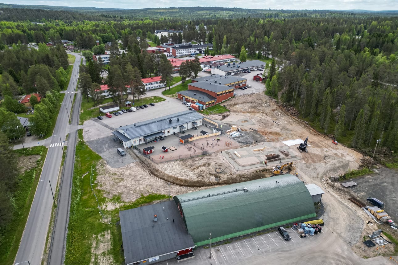 Taivalkosken keskustan Urheilutie (vasemmalla) ympäristöineen kesäkuussa 2025. Oikealla etualalla on Kaarihalli ja sen takana päiväkoti Pikkupeikon työmaa.