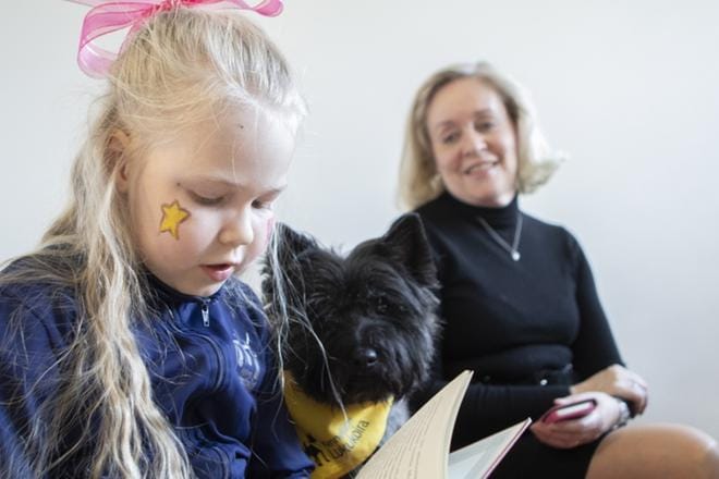8-vuotias Olivia Samppala lukee keskittyneenä kirjaa ja Kennelliiton lukukoira Oiva kuuntelee kiinnostuneena. Jalasjärven kirjaston kirjastovirkailijan Päivi Samppalan mukaan koiran läsnäolo rentouttaa lukijaa. Jalasjärvellä lukukoiratapaamisia on järjestetty kohta parin vuoden ajan. KUVA: LIISA SORAMO