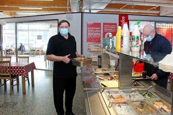– Asiakkaat voivat syödä myös tuolta takaa vapautuneessa liiketilassa, sanoo Lounasravintola Jonnan yrittäjä Jarmo Etula (vas.). Vieressä asiakas Olli Sulkakoski kokoaa annostaan. KUVA: MIA KÄRKKÄINEN