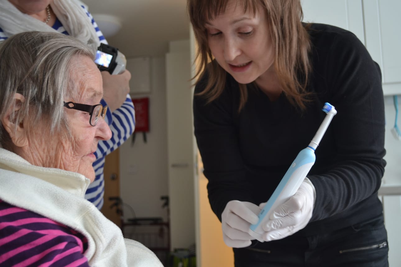 Suuhygienisti Paula Aikkila esittelee sähköhammasharjaa. Se on uusi tuttavuus 93-vuotiaalle Iida Paasovaralle.