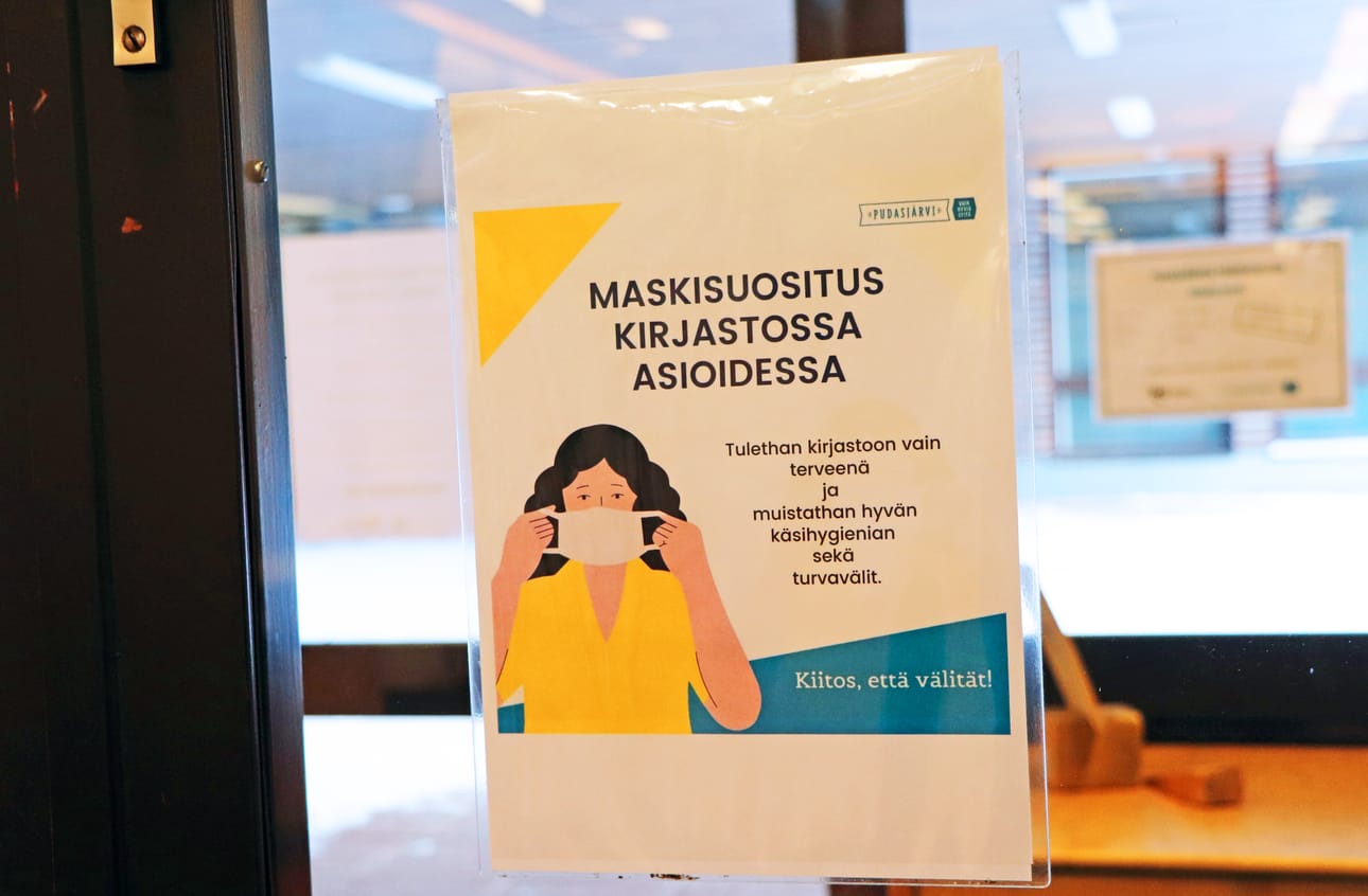 Pudasjärven kirjaston ovessa muistutetaan asiakkaita maskisuosituksesta.