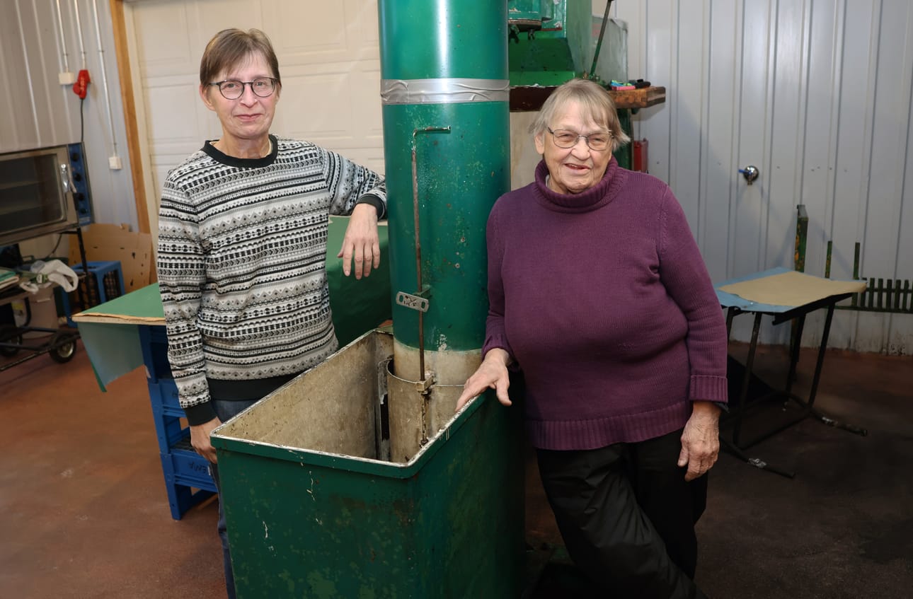 Anne Juntunen ja Raili Pirttinen nojaavat puristimeen, joka on palvellut mehuasemaa yrityksen perustamisesta lähtien. – Pieniä korjauksia on tehty, mutta hyvin vähän niitäkin, Juntunen tietää.