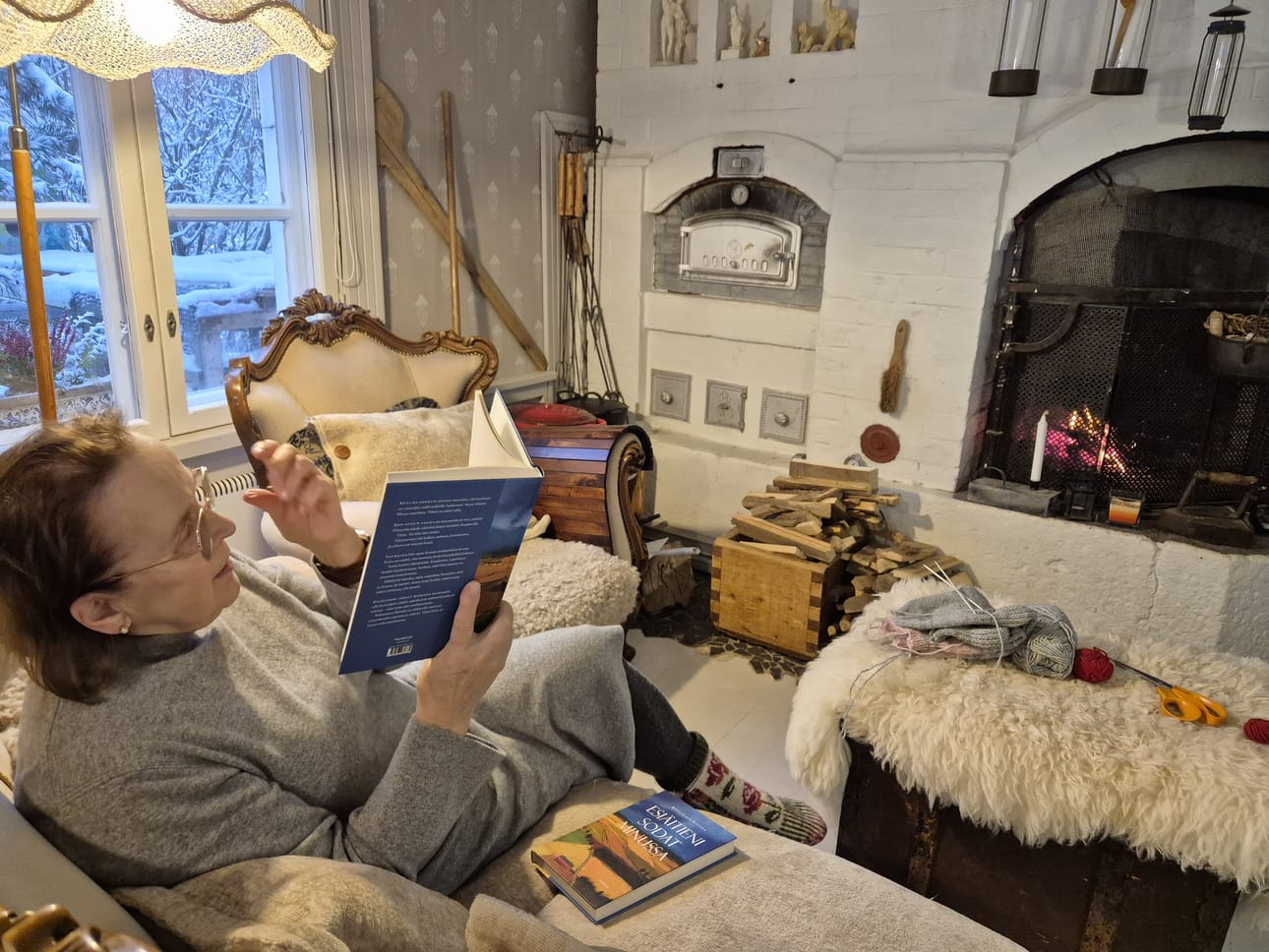 Riittamaria Rintala istuu usein takkatulen ääressä lukemassa.