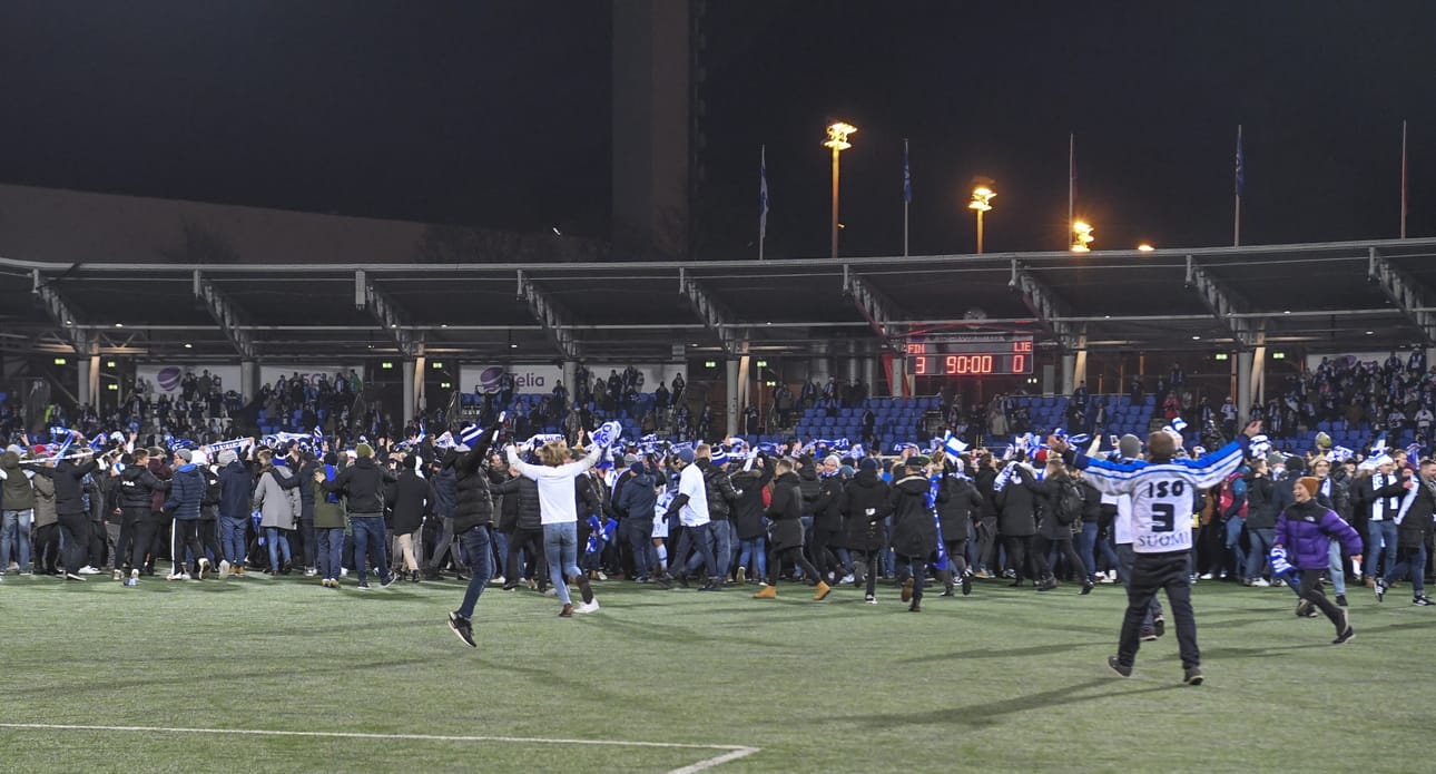 Suomalaiset kannattajat juhlivat historian ensimmäistä miesten jalkapallon EM-kisapaikkaa Töölön jalkapallostadionilla Helsingissä 15. marraskuuta juoksemalla kentälle.