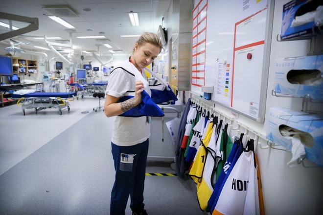 Sairaanhoitaja Jessica Nylund pukee rooliliivin päälleen päivystyksessä. Siitä selviää heti, missä tehtävässä kukin on. KUVAT: JARNO PELLINEN