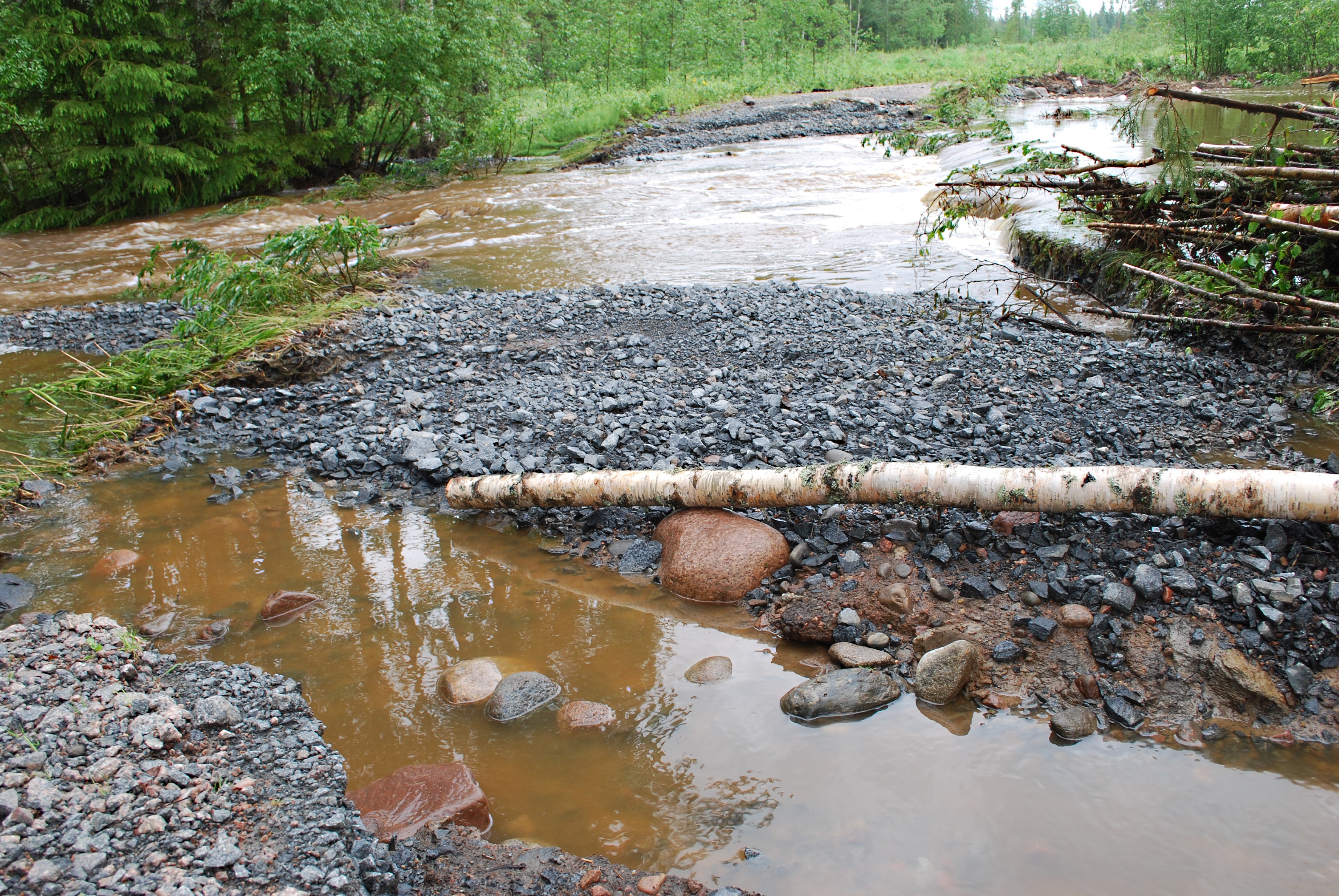 Matkanivassa olevan Knuutilantien varressa vesi virtaa vuolaasti pikkuteiden yli.