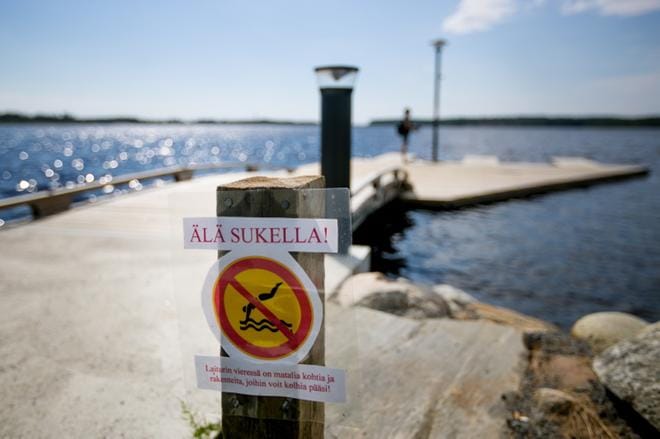 Sukeltamisesta varoittavia kylttejä on laiturilla yhteensä kolme. Yksi osuu silmään jo laiturille mentäessä ja kaksi kieltokylttiä on sijoitettu myös laiturilla olevaan valaisinpylvääseen. Melojat pelkäävät, koska joku pääsee hengestään uhkarohkealla sukeltamisellaan. KUVA: JAAKKO ELENIUS
