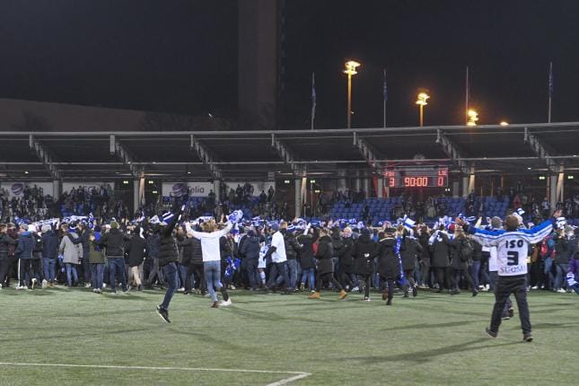Suomalaiset kannattajat juhlivat historian ensimmäistä miesten jalkapallon EM-kisapaikkaa Töölön jalkapallostadionilla Helsingissä 15. marraskuuta juoksemalla kentälle. KUVA: KIMMO BRANDT