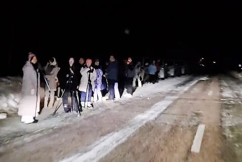 Kymmenet turistit seisoivat keskellä yötä maantien varressa.