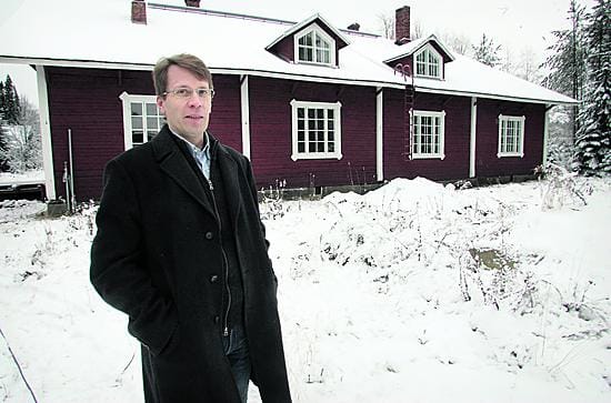 Toimitusjohtaja Olli Karhi myhäilee tyytyväisenä vanhan miehistökasarmin edessä. Rakennus säilyttää perinteisen ilmeensä punamultaisine hirsiseinineen, peltikattoineen ja valkoisine nurkkalautoineen.