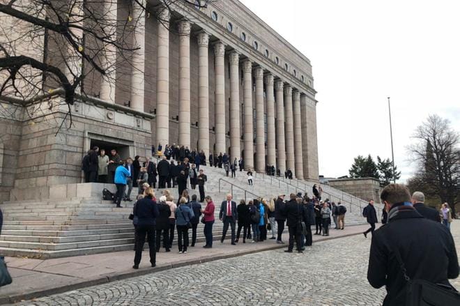 Eduskuntatalosta palohälytyksen vuoksi ulos joutuneet ihmiset odottivat sisäänpääsyä eduskuntatalon portailla torstaina. KUVA: LASSE HAUTALA